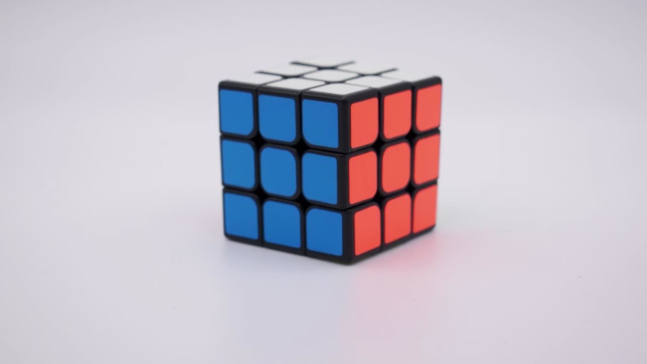 primer plano del cubo de rubik resuelto cayendo en el marco con un fondo blanco limpio