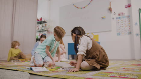 Kleines-Mädchen-Und-Kleiner-Junge-Spielen-Mit-Verschiedenen-Stücken-Auf-Dem-Teppich-Im-Klassenzimmer-In-Einer-Montessori-Schule