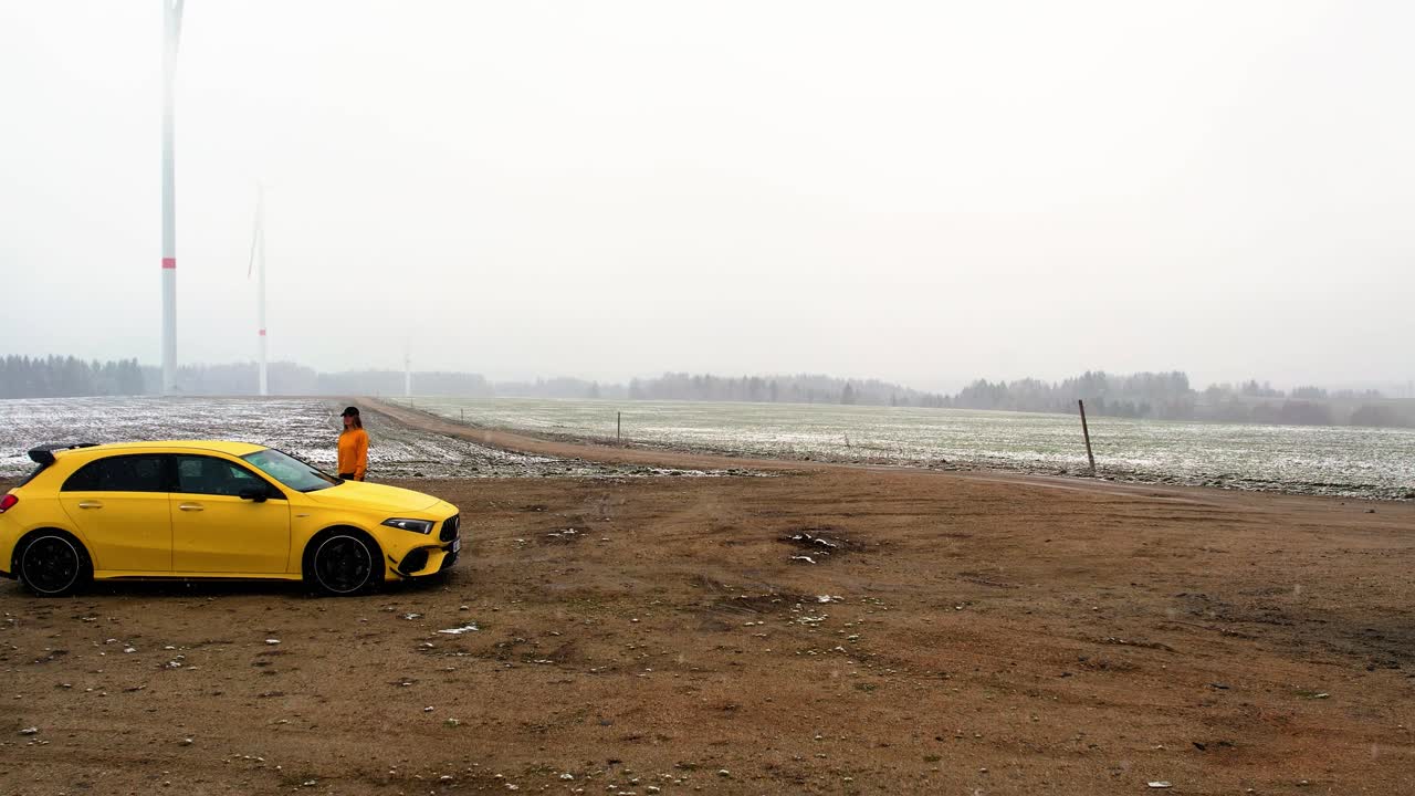 Woman Walking to a Yellow Car in Snow - Aerial Dolly shot, Slow-motion