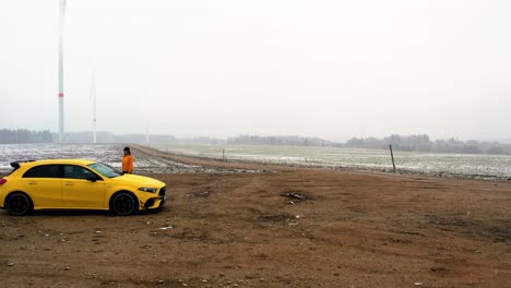 woman walking to a yellow car in snow - aerial dolly shot, slow-motion