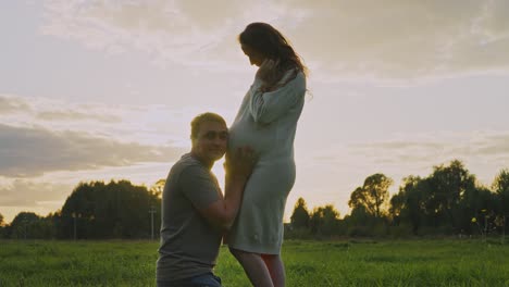 pregnant woman and partner enjoying sunset in the field