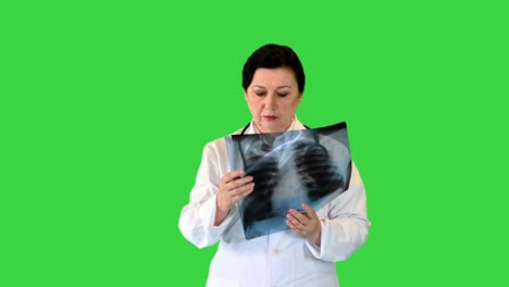 female doctor examining lungs x-ray while walking on a green screen, chroma key