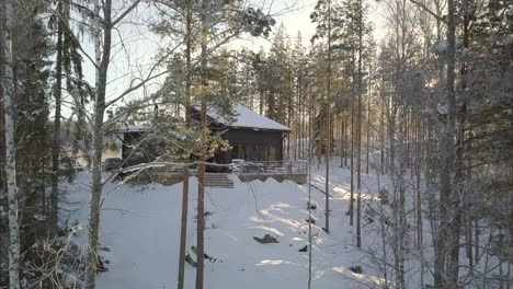 Cinematic-Reveal-of-Golden-Morning-Sunrays-on-Hidden-Forest-Hut-in-Snowy-Landscape