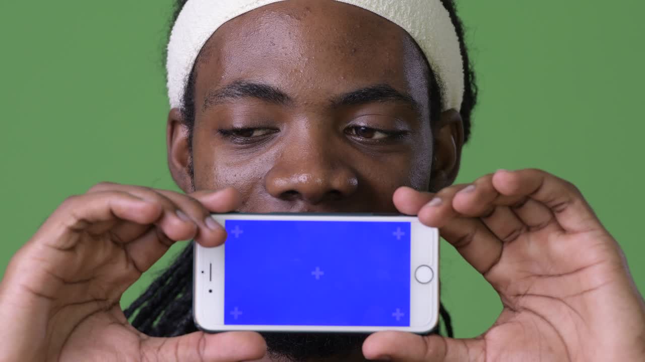 joven hombre africano guapo con dreadlocks contra un fondo verde