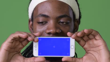 young handsome african man with dreadlocks against green background