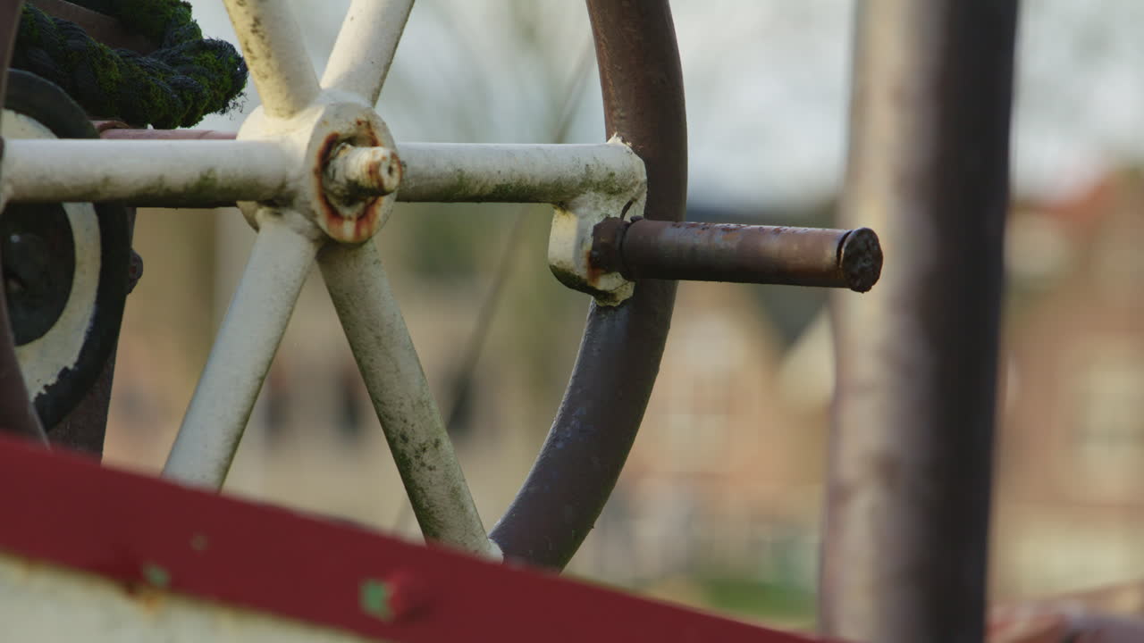 Primo piano di un volantino in metallo consumato su attrezzatura marittima vintage, che simboleggia controllo, meccanica, industria e artigianato nautico con profondità di campo ridotta