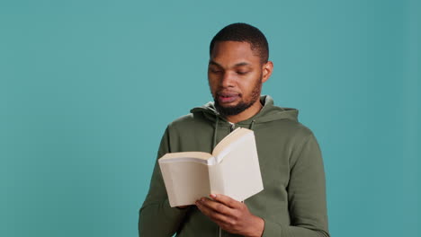 Man-laughing-while-reading-funny-book,-entertained-by-story