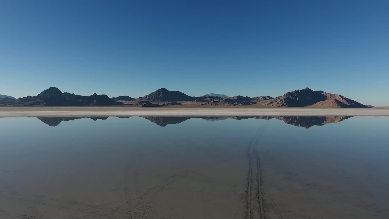 una toma aérea de aguas tranquilas que cubren las salinas de bonneville refleja montañas distantes