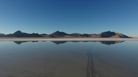 an aerial drone shot of smooth water covering the bonneville salt flats reflects distant mountains