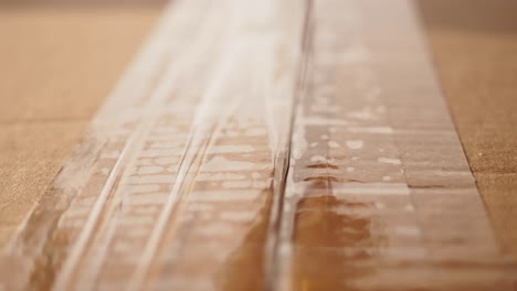 close-up of clear packing tape being applied to a cardboard box
