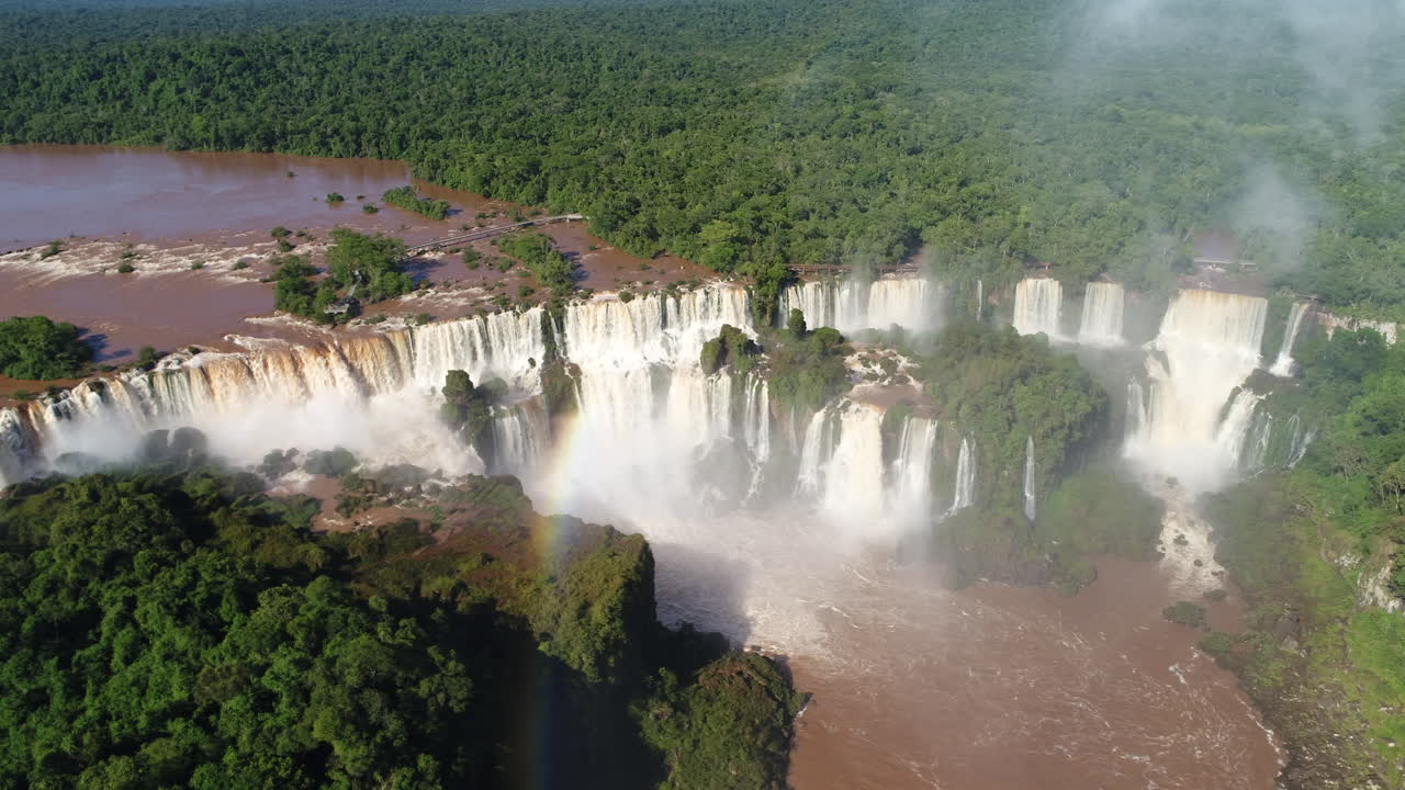 una vista impresionante de las cataratas de iguazu en un hermoso día, adornadas con un vibrante arco iris