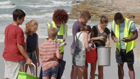 Vorderansicht-Von-Afroamerikanischen-Freiwilligen,-Die-Die-Abfälle-Der-Teilnehmer-Am-Strand-Kontrollieren,-4k