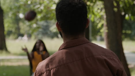 a man and woman playing with a ball in a park