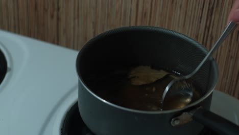 close-up static shot of spoon mixing brine being heated in a saucepan.