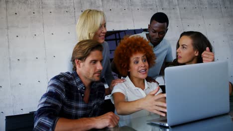 team of executives discussing over laptop