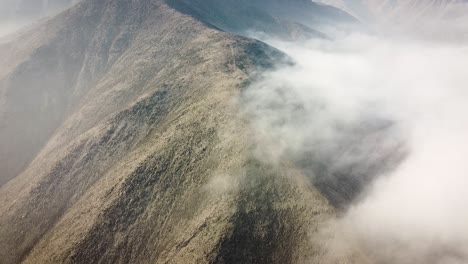 Drone-shot-of-a-mountain-crest-with-a-misty-cloud-during-sunrise-in-the-city-of-Lima