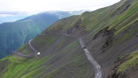 wide cinematic angle drone shot of vehicle driving on the road to tusheti in the caucasus mountains, one of the worlds most dangerous roads