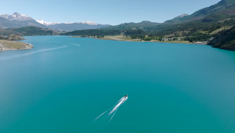 vuelo aéreo sobre el suave lago turquesa general carrera con lancha rápida pasando