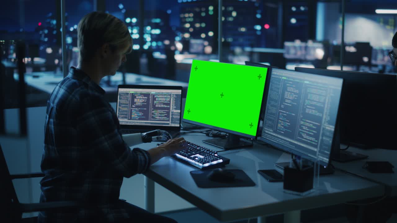 oficina nocturna: persona con discapacidad que utiliza un brazo protésico para trabajar en una computadora de pantalla verde. uso rápido y natural de la mano myoeléctrica biónica para escribir código para software por la noche. arco medio