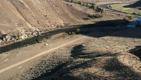 Drone-footage-from-the-side-of-a-backcountry-single-engine-plane-landing-on-a-remote-landing-strip-surrounded-by-mouintains-and-a-river-in-the-Frank-Church-River-of-No-Return-Wilderness-in-Idaho