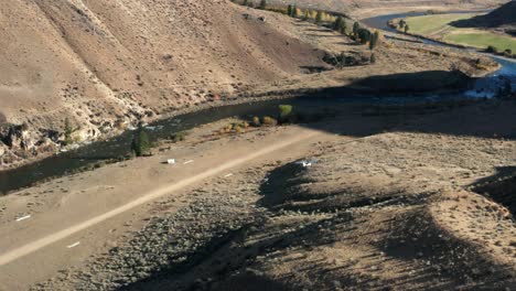 imágenes de drones desde el lado de un avión monomotor de backcountry aterrizando en una pista de aterrizaje remota rodeada de montañas y un río en el río frank church de no retorno desierto en idaho