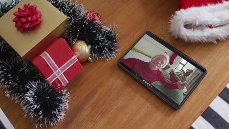 hombre afroamericano albino sonriente con sombrero de santa en una videollamada de navidad en una tableta