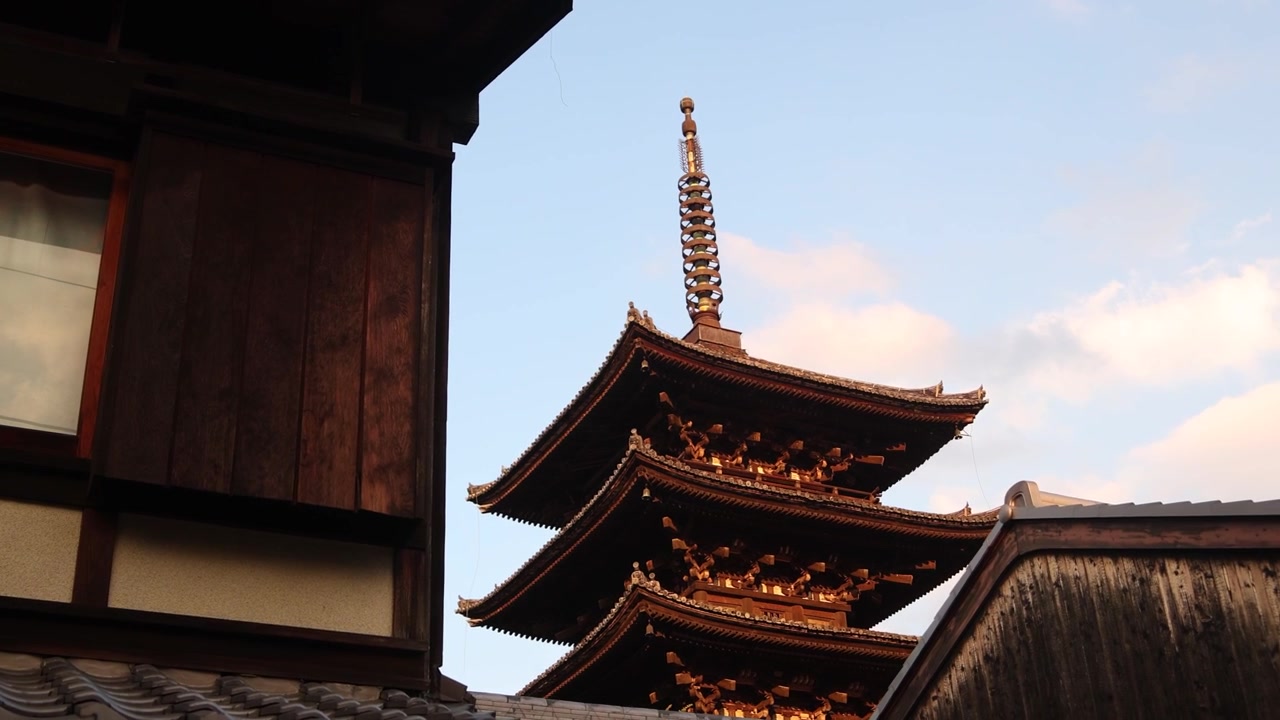 Yasaka Pagoden rejser sig bag en traditionel træbygning i Kyotos Higashiyama-distrikt, der kombinerer lagdelt tempelarkitektur med det bevarede gadebillede og tagene fra det gamle Japan