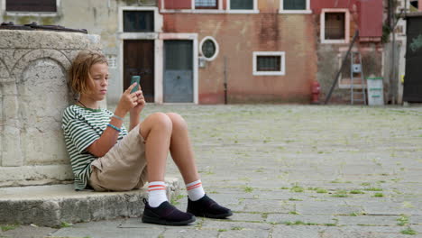 teenager engrossed in smartphone at venetian square