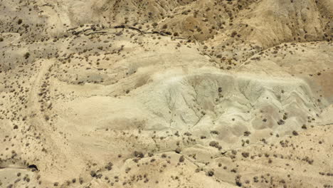 drone view flying over the dry sandy mountains in the rainbow basin part of the mojave desert