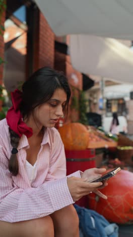 young woman using phone at a street market