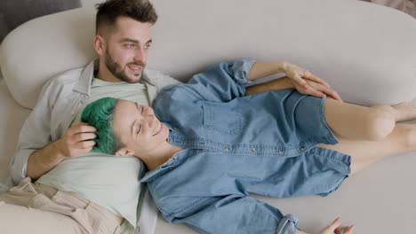 top view of young couple sitting on sofa, talking and caressing each other