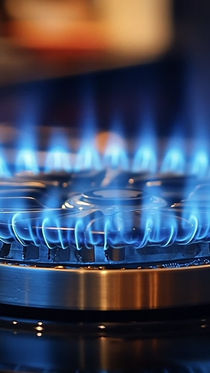 Gas burner flame in a modern kitchen. Bright blue flame emanates from a gas burner, illuminating a sleek kitchen setup during evening cooking.