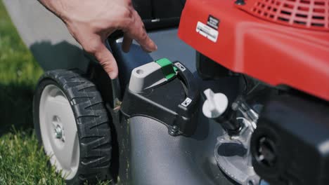 Detail-of-a-man-adjusting-a-gas-mower-mode-on-a-sunny-day-on-a-green-lawn