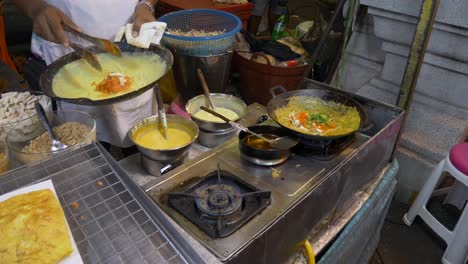 cooking omelette with vegi at asian street night market street food booth in hot summer