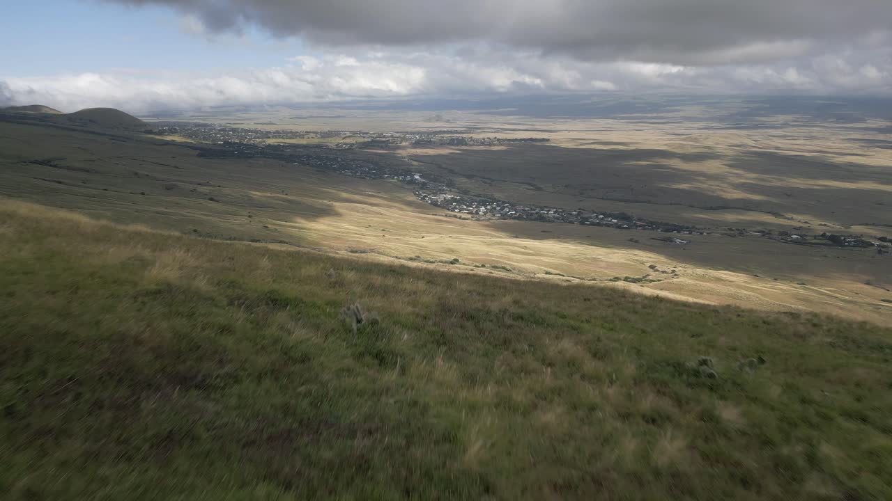 crestas aéreas cima de la colina verde para revelar la pendiente de prado expansivo a la ciudad