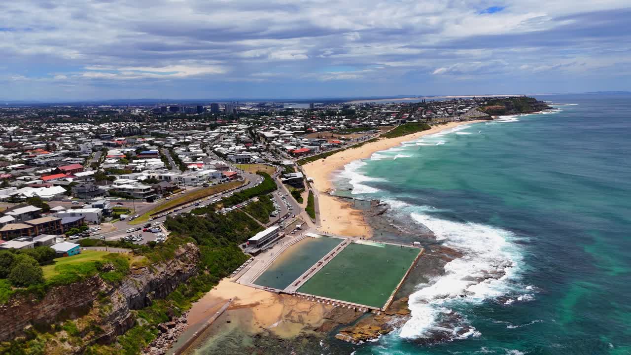 Ampio panorama aereo di Merewether Beach e della piscina che curva lungo la costa di Newcastle, orbita stabilita
