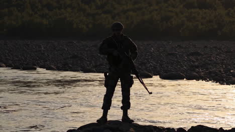 soldier on patrol near river at sunset