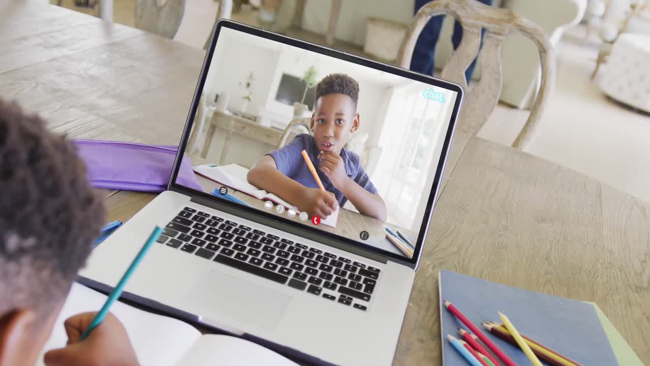 African american boy using laptop for video call with african american school friend on screen