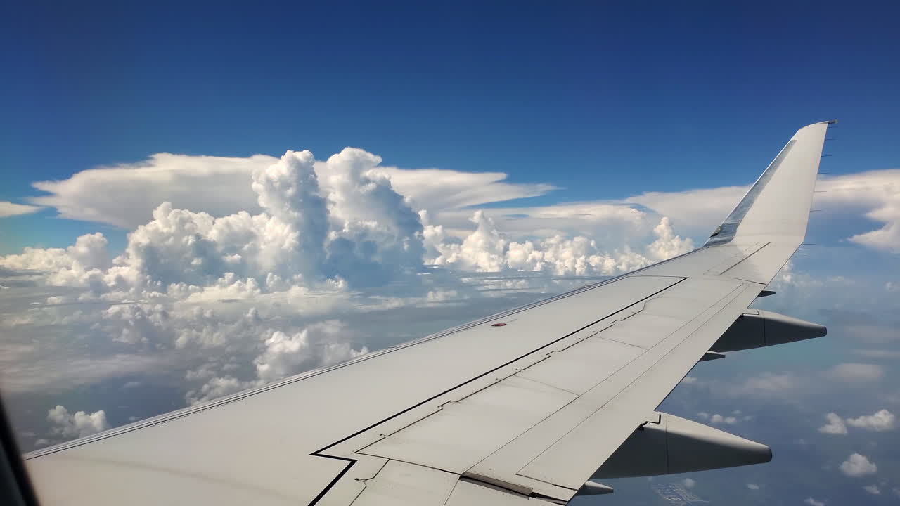 Pretty 4k shot of airplane wing with clouds and blue sky