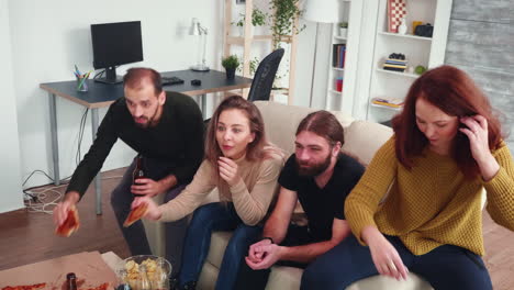 group of four friends watching a movie in living room