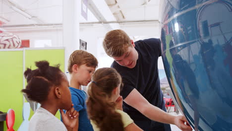 School-kids-looking-at-globe-with-teacher-at-science-centre