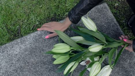 woman placing lilies on a grave