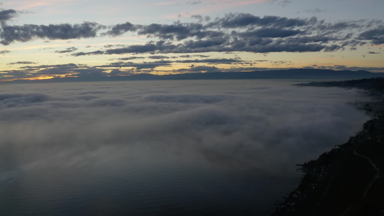 Aerial panning over fog covering lake Léman at sunset