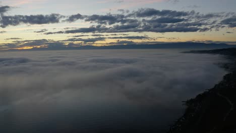 Panorámica-Aérea-Sobre-La-Niebla-Que-Cubre-El-Lago-Léman-Al-Atardecer