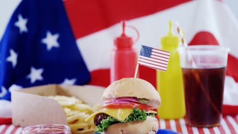 hamburger and cold drink arranged on tablecloth