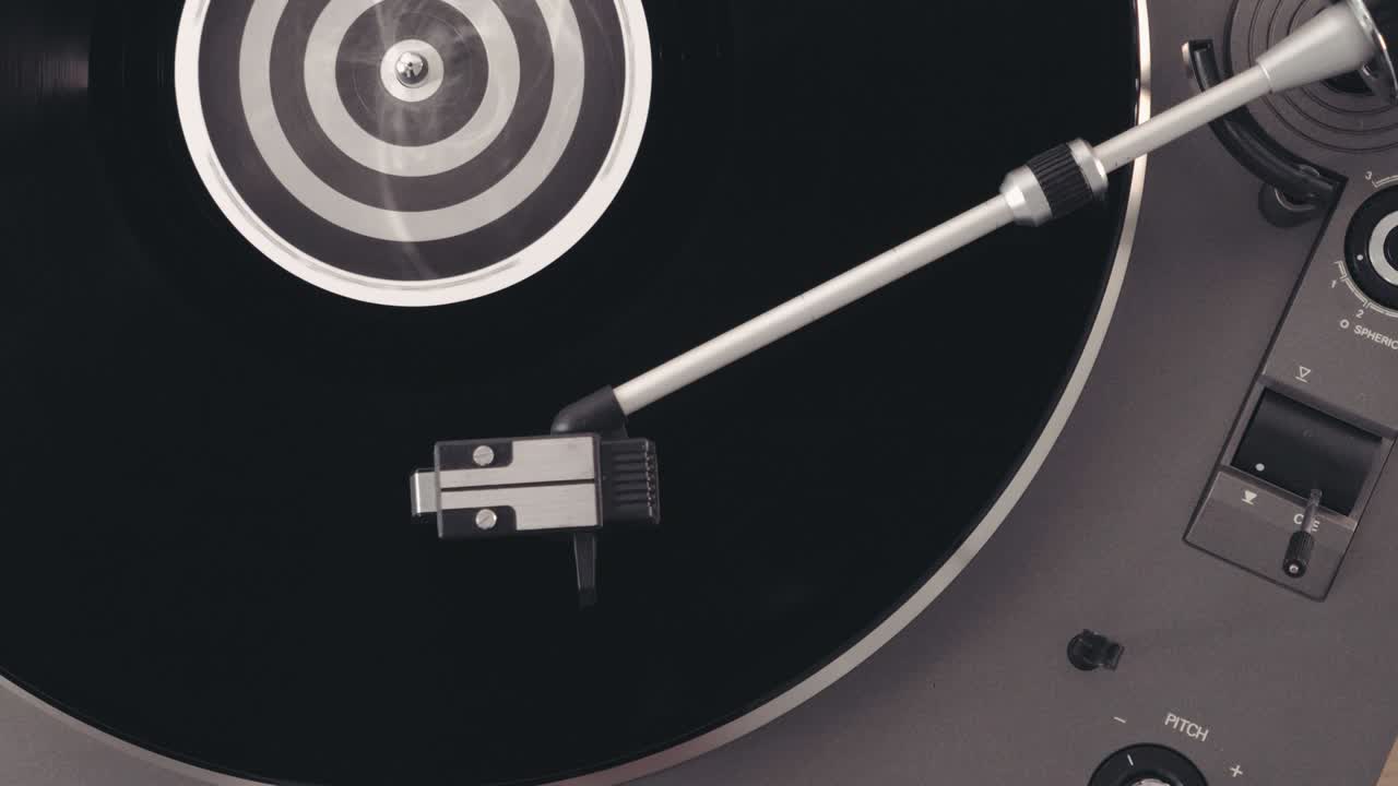 фрагмент вращающегося черного винилового проигрывателя. вращающаяся пластина и стилус с игловой поворотной столой вблизи. черный виниловый фон с зеленым экраном в центре