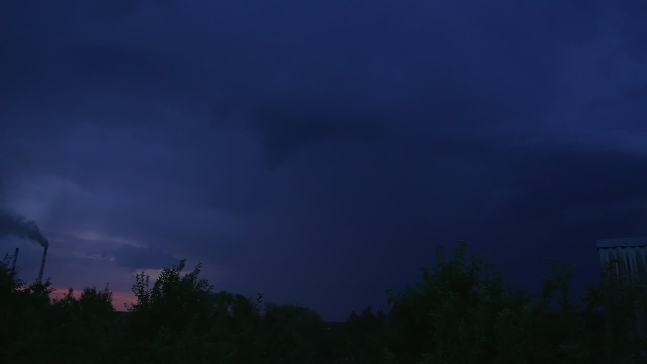 Storm and lightning in the rural countryside. Tops of trees swaying in the wind. Night skies lit by thunderstorm.