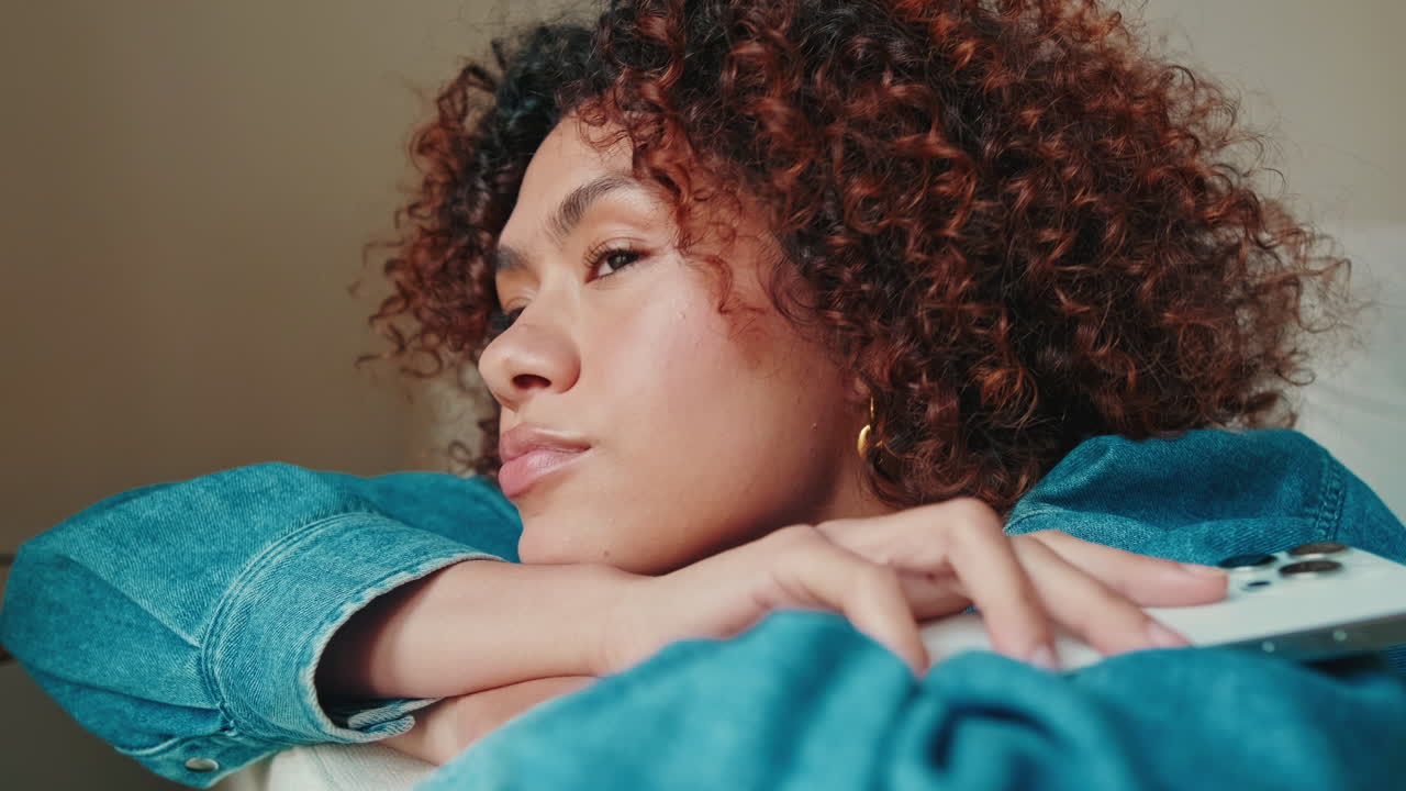Young Woman with Curly Hair Resting and Looking Thoughtfully