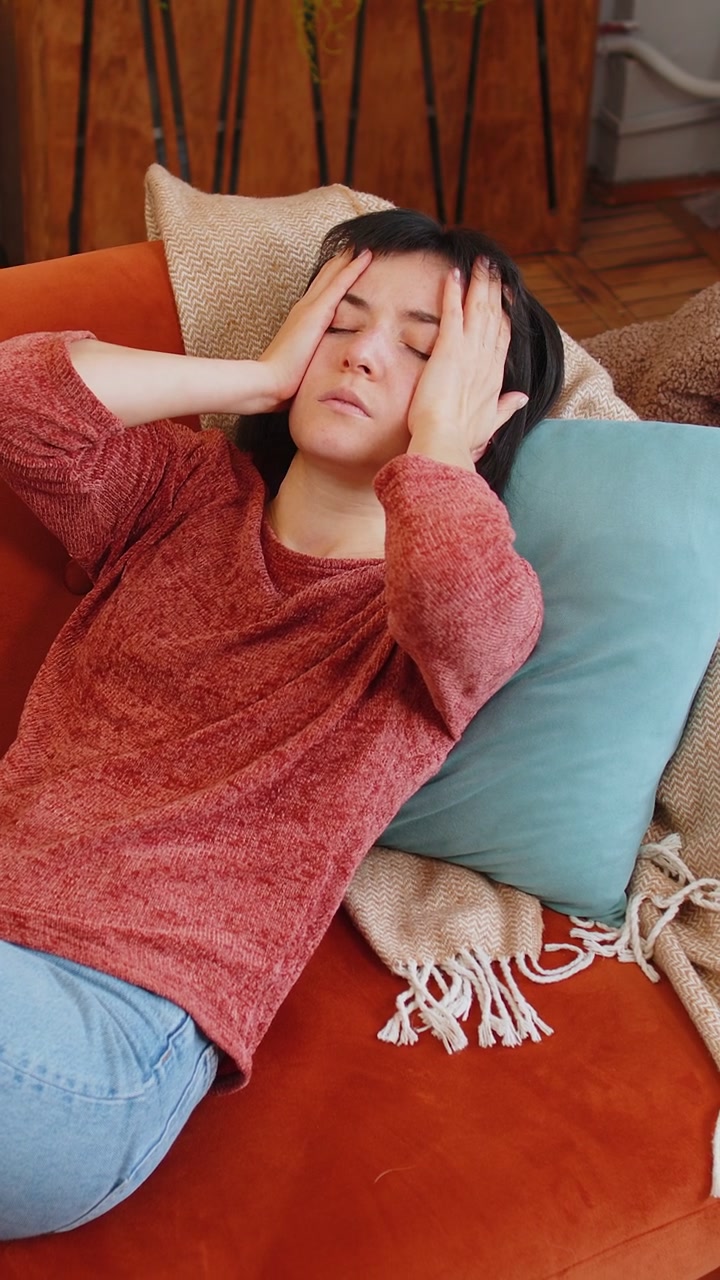 Donna sconvolta si massaggia le tempie per alleviare il mal di testa causato da tensione, emicrania e stress