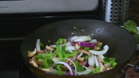 volteando las verduras en la sartén mientras cocina